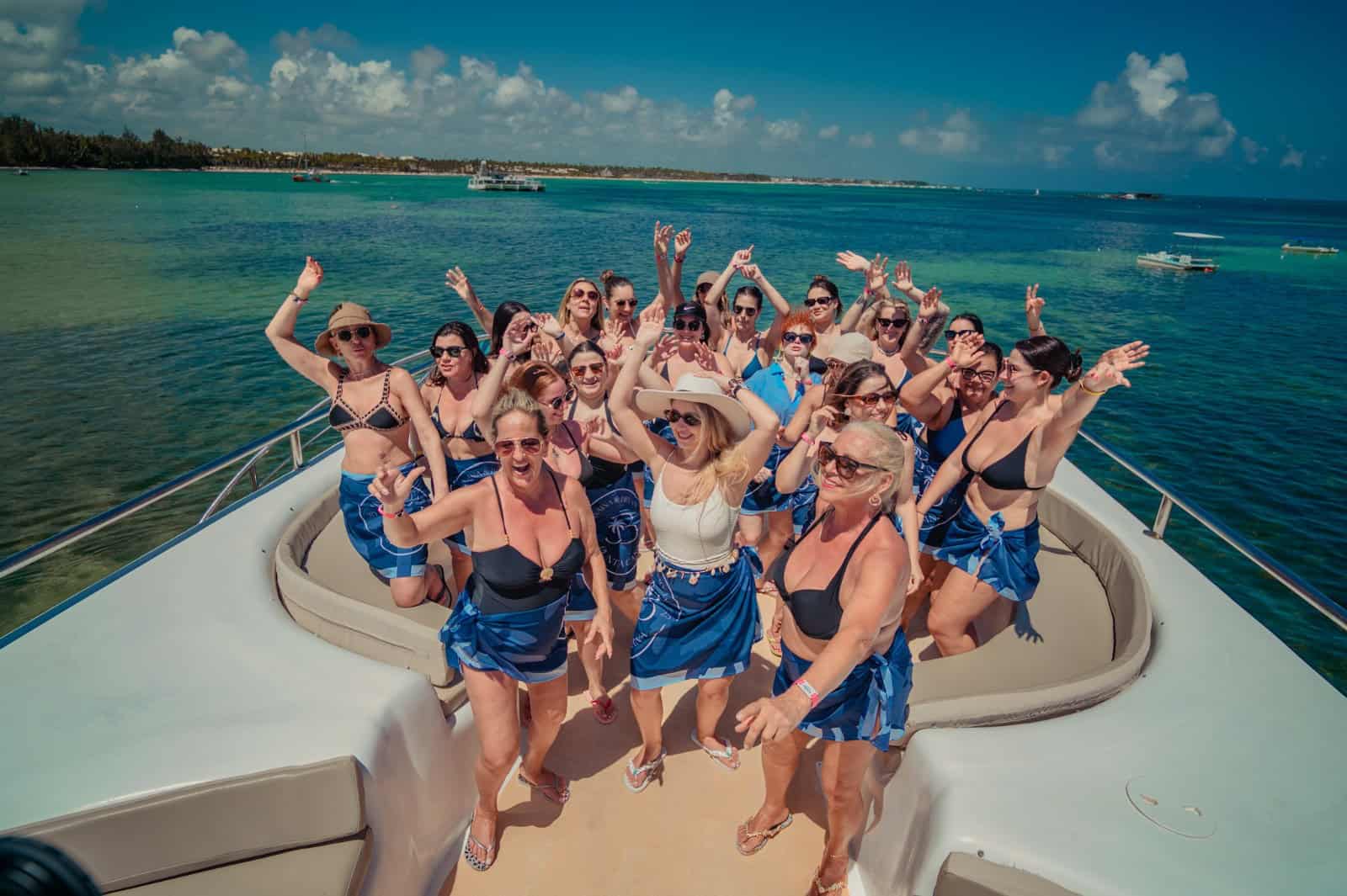 Convidados celebrando destination wedding em barco com mar azul no verão.