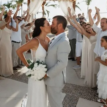 Elaine e Rafael se beijando após a cerimônia, com os convidados comemorando