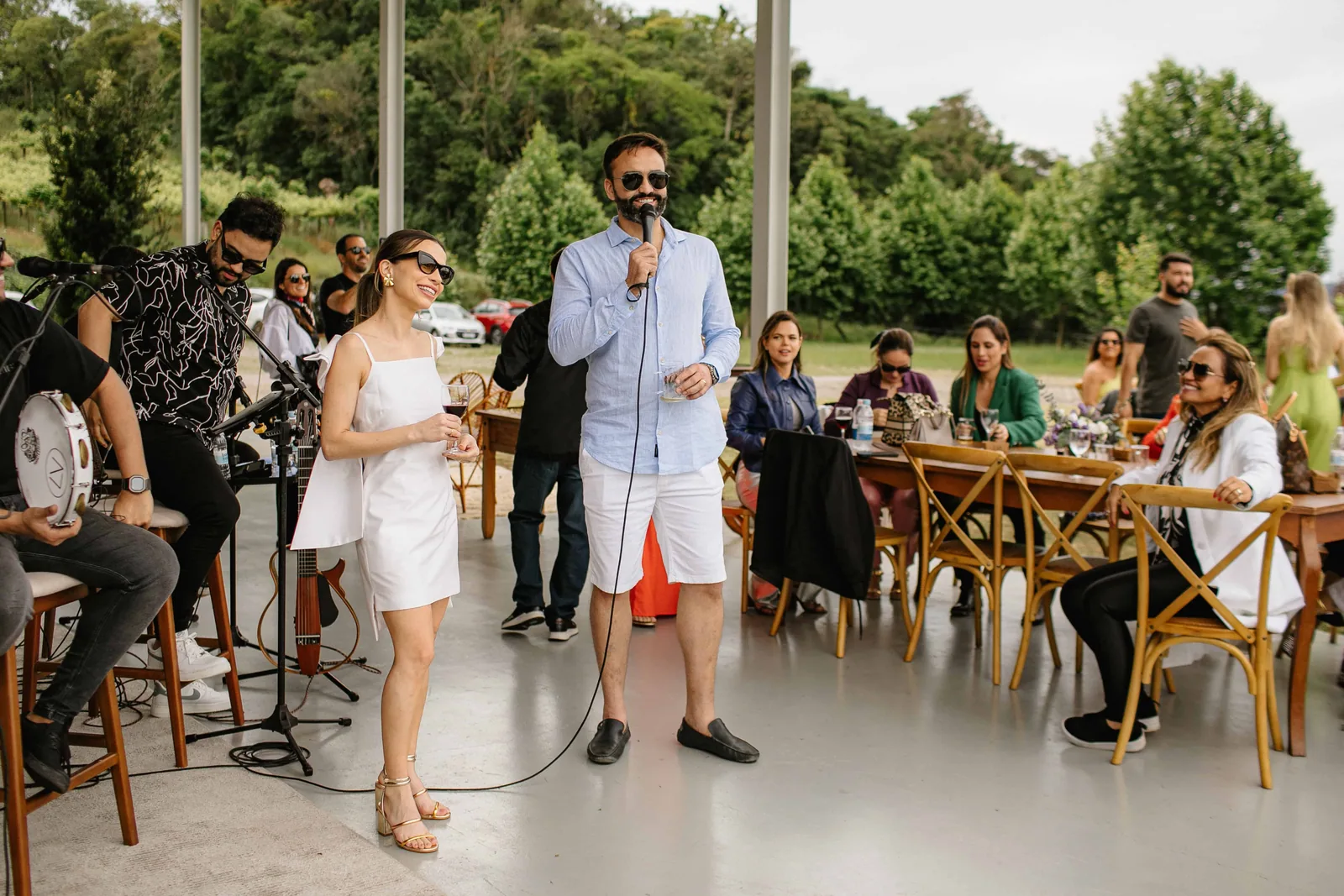 Banda tocando ao vivo na festa de casamento, com os convidados sentados nas mesas ao fundo