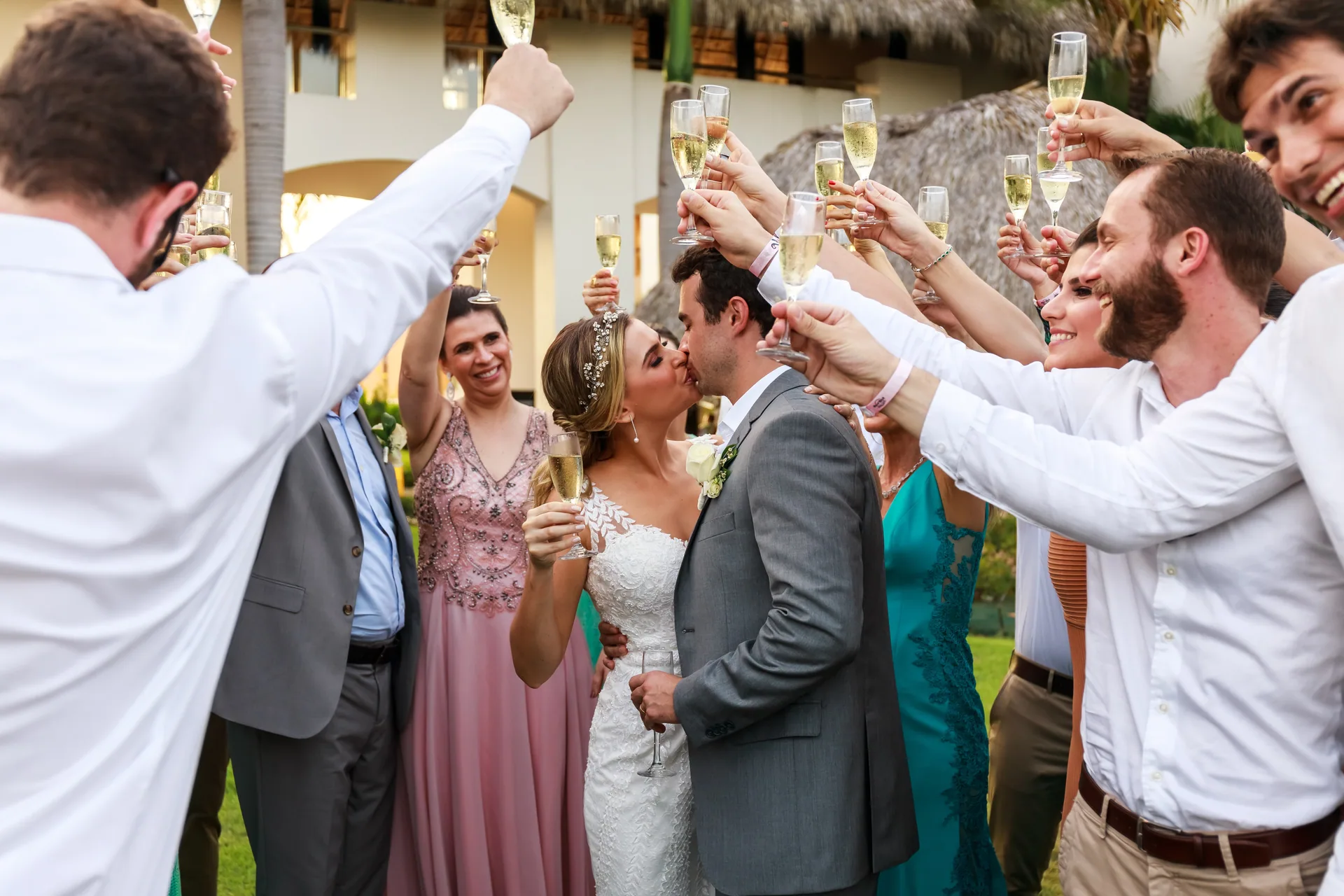 Convidados brindando em roda enquanto o casal se beija, na festa de casamento